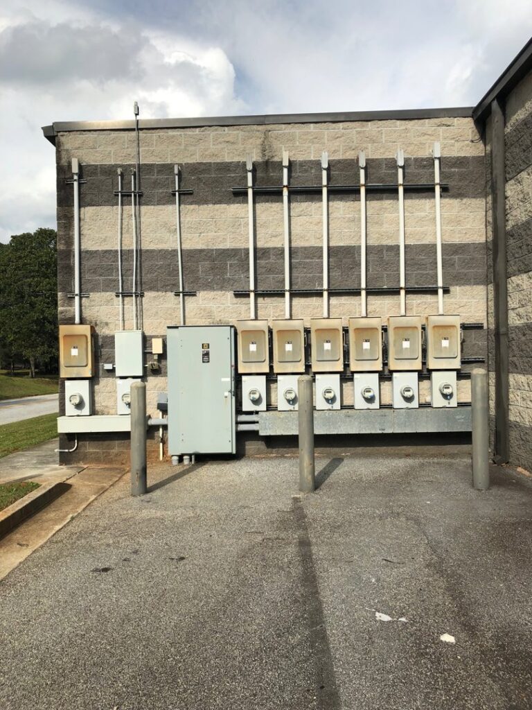 Exterior view of a commercial building showing multiple electrical meters and conduits by McCall Enterprises in Atlanta, GA.