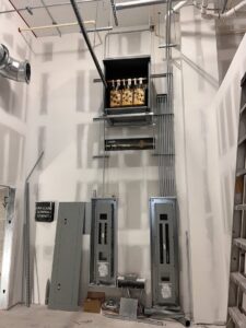 Multiple electrical panels and conduits professionally installed on a wall in a commercial building by Krakkom Electric in Sunrise, FL.