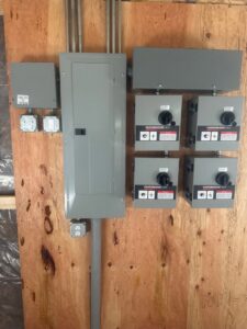 Commercial electrical panels and control switches installed on a wooden wall by Minards Electric LLC in Dickinson, ND.