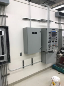 Multiple electrical panels and conduits neatly installed on a wall, demonstrating commercial electrical work by Premier Electric LLC in Palmer, AK.
