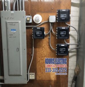 A commercial electrical panel with multiple sub-meters installed on a wooden wall by Kouris Electric LLC in Canton, OH.