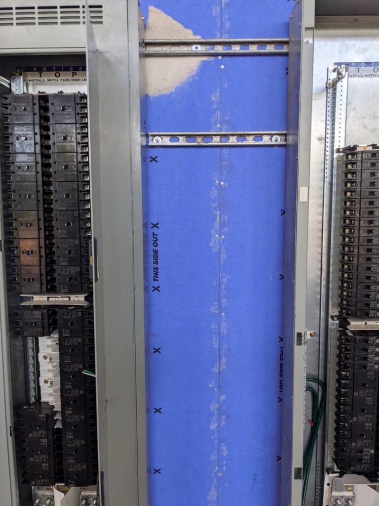 Interior view of a commercial electrical panelboard with numerous circuit breakers, handled by GOBE LLC in Columbia, MO.