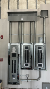 Multiple commercial electrical panels and conduits installed on a wall, showcasing professional work by JL's Electric Inc. in Norman, OK.