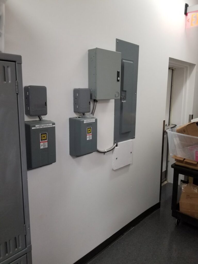 Multiple electrical panels and boxes mounted on a commercial wall, installed by KS Retail Solutions in Victoria, TX