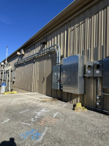 Exterior view of a commercial building showing multiple electrical panels, meters, and conduits installed by Pro Circuit Electric in Peoria, IL.