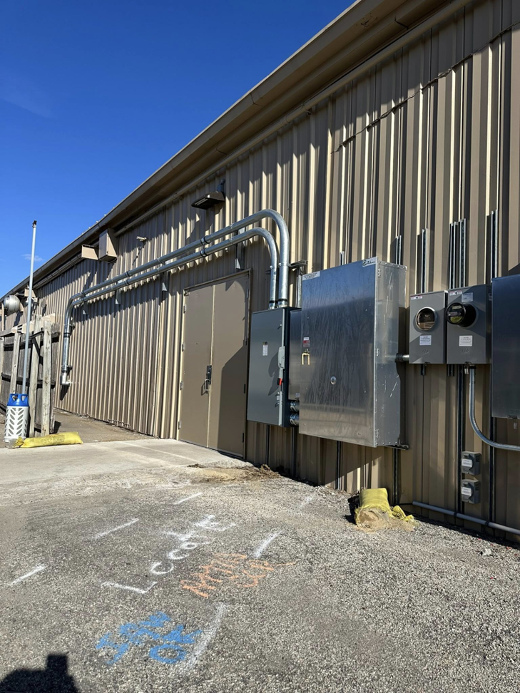 Exterior view of a commercial building showing multiple electrical panels, meters, and conduits installed by Pro Circuit Electric in Peoria, IL.