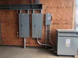 Commercial electrical panels and a transformer installed on a wooden wall by Patriot Electric L.L.C in Phoenix, AZ