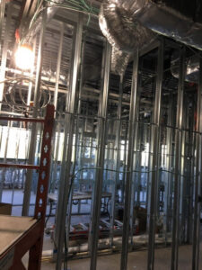 Commercial electrical rough-in at a construction site with metal studs and temporary lighting by RTF Electric LLC in Toms River, NJ.