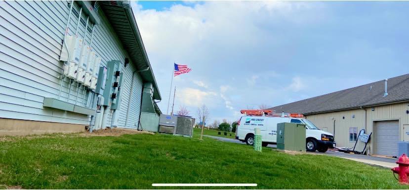 A Pro Circuit Electric service van parked outside a commercial building with outdoor electrical units in Peoria, IL.