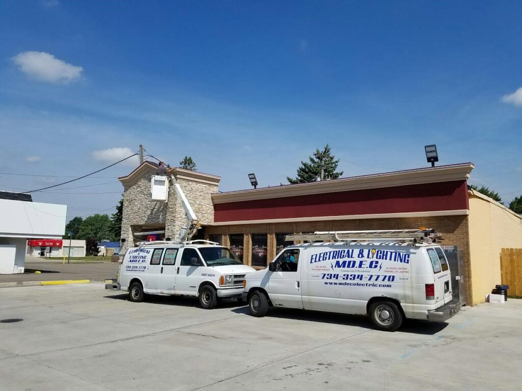 MDEC Electrical & Lighting service vans with a bucket lift performing commercial electrical work in Livonia, MI.