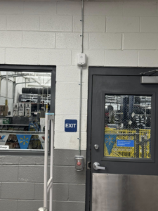 A commercial exit sign and emergency exit button system with electrical conduit installed near a door by Flash Construction in Winifrede, WV.