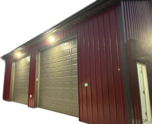 Commercial exterior lighting installed above garage doors on a red metal building by Blevens Electric LLC in Bowling Green, KY