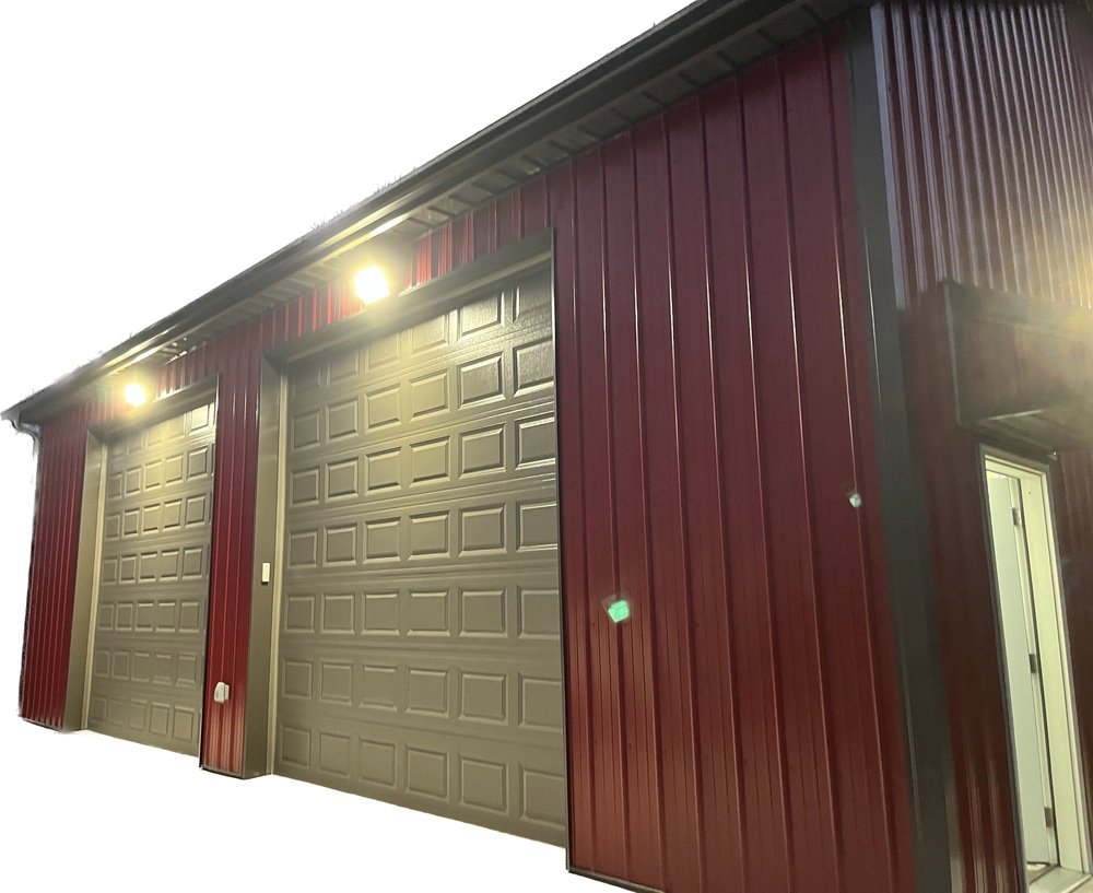 Commercial exterior lighting installed above garage doors on a red metal building by Blevens Electric LLC in Bowling Green, KY