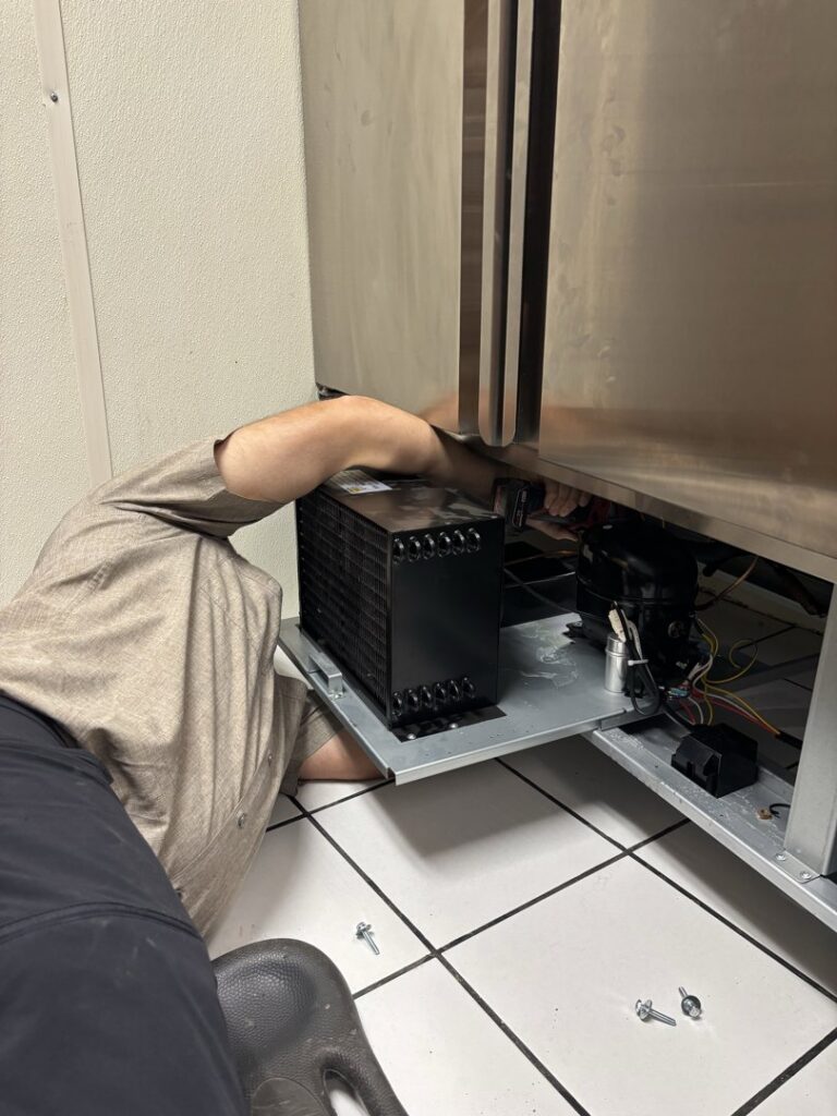 An HVAC technician repairing the condenser coil of a commercial freezer for Polar Air Heating and Cooling in Omaha, NE