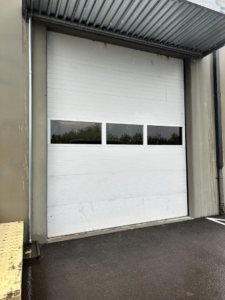 A newly installed white commercial garage door with windows by DOOR TECHS in Salem, OR.