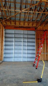Commercial garage door installation in progress with ladders and tools inside a building by Ken's Overhead Door in Clarksville, TN.