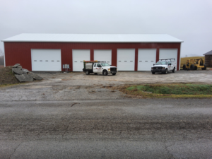 Commercial garage door installation with Phelps Dock and Door service trucks in front of a red building in Cave City, KY.