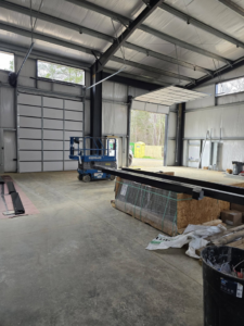 A commercial garage door installation site with one door open and one closed by Coles Garage Door Service, LLC in West Columbia, SC.