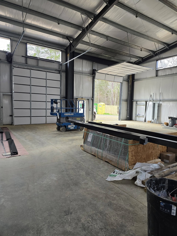 A commercial garage door installation site with one door open and one closed by Coles Garage Door Service, LLC in West Columbia, SC.