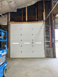 A white commercial garage door installed inside a building by Strongdoor garage in Denver, CO.