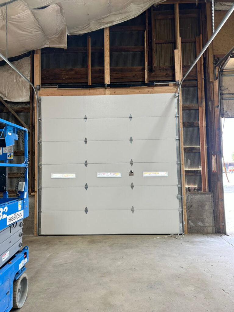 A white commercial garage door installed inside a building by Strongdoor garage in Denver, CO.