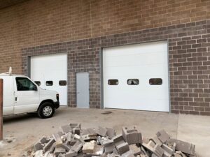 Two newly installed commercial garage doors on a brick building by Team Garage Doors in Mesa, AZ.