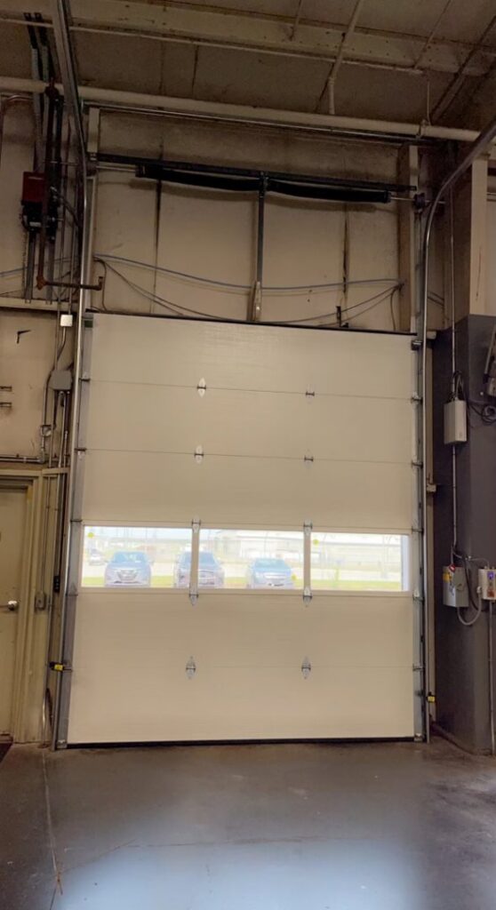 Interior view of a commercial garage door showing tracks and opener system by Summers Garage Door in Denver, CO.