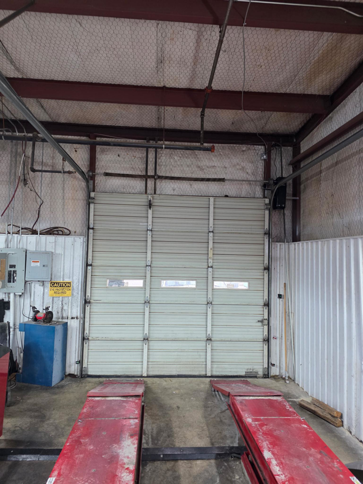 An interior view of a commercial garage with a large white sectional garage door by APEX Garage Doors and Carports in Lawton, OK.