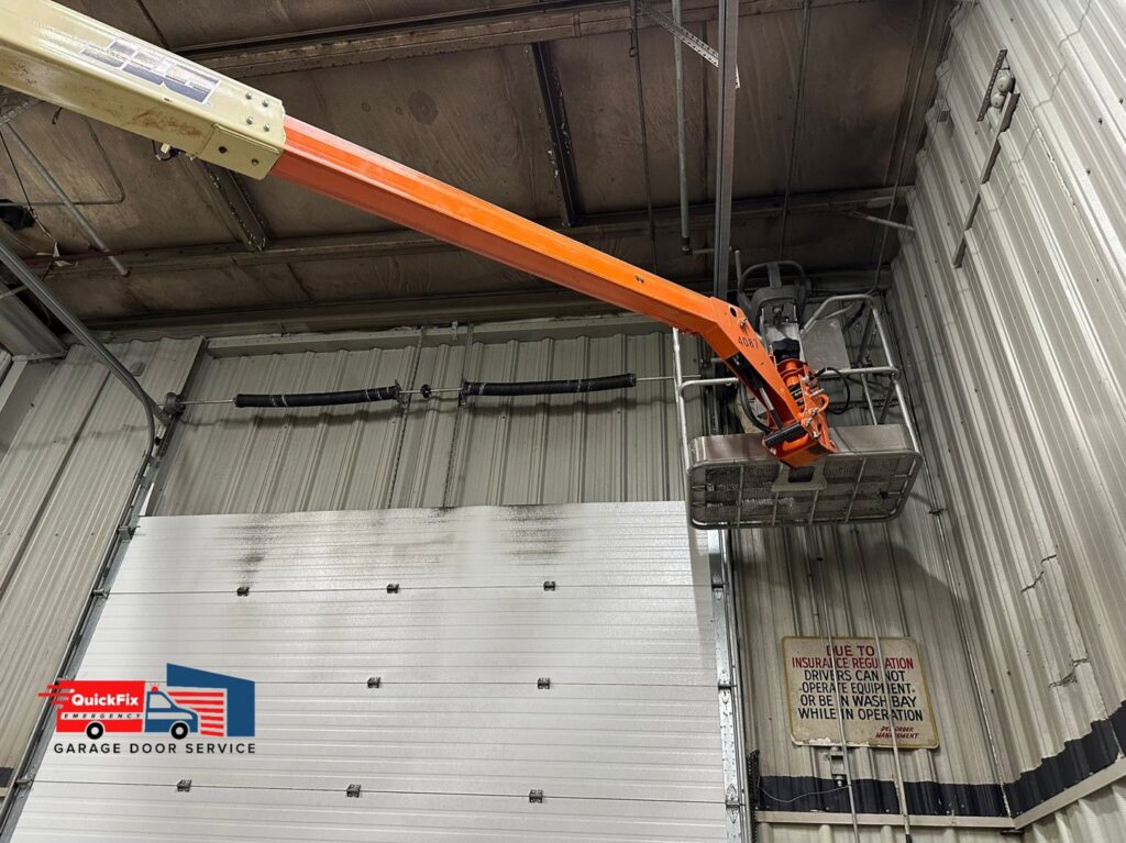A technician using a lift to perform maintenance on a commercial garage door for QuickFix Garage Door Service in Brighton, MA.