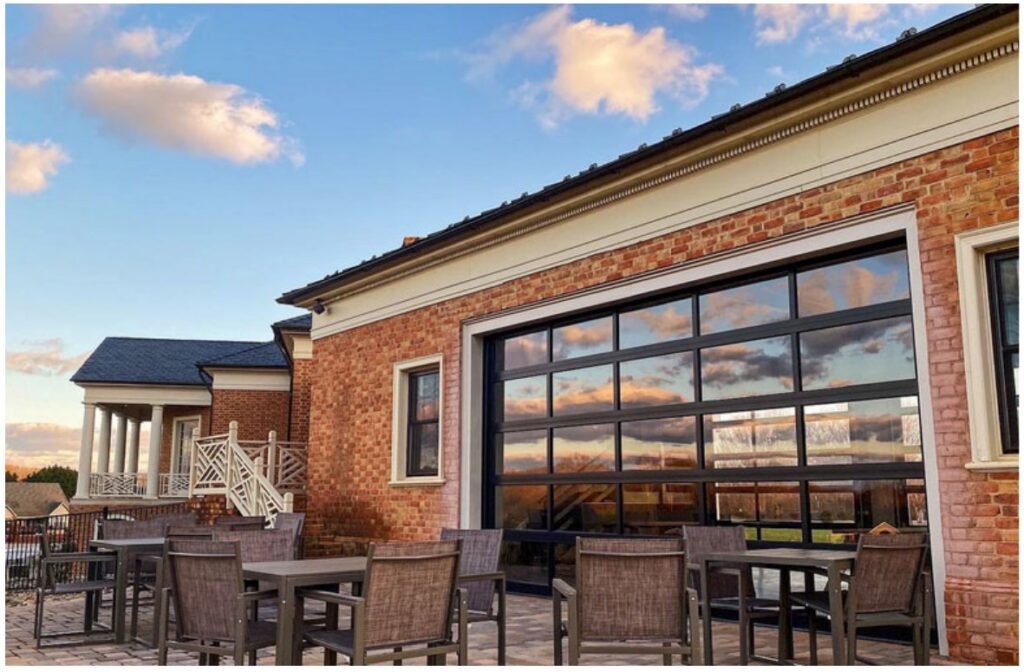 A large commercial glass garage door on a brick building, opening to an outdoor patio, installed by Geiszler Garage Door in Milwaukee, WI.