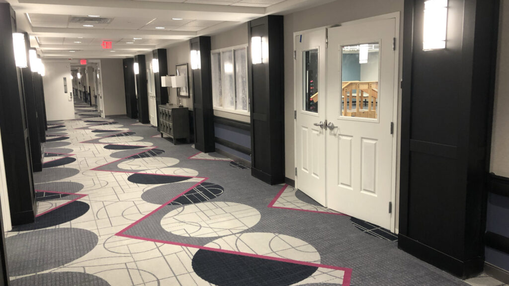 A long commercial hallway featuring a modern patterned carpet installation by Aaron's Facility Services in Detroit, MI.