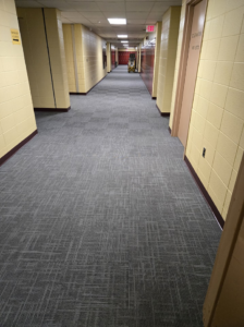 A long commercial hallway featuring newly installed grey carpet tiles by Chenards Carpet in New Bedford, MA.