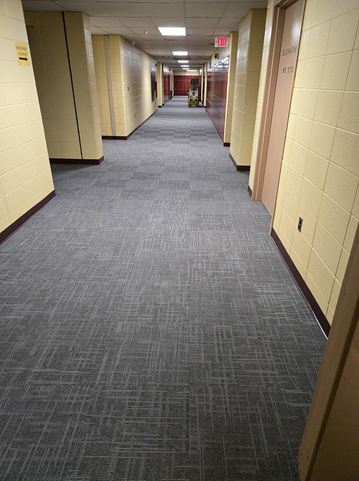 A long commercial hallway featuring newly installed grey carpet tiles by Chenards Carpet in New Bedford, MA.