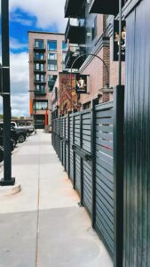 A sleek black commercial horizontal slat fence installed along a sidewalk by Complete Fence, LLC in West Chicago, IL