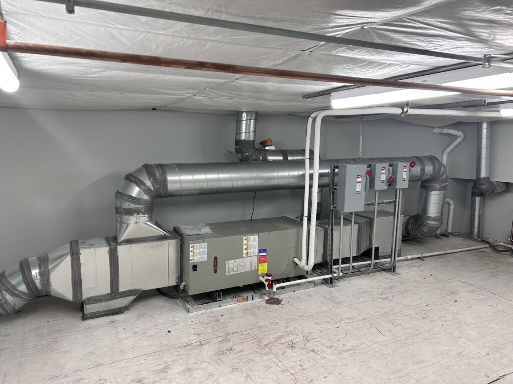An indoor commercial HVAC air handler unit with extensive ductwork installed by KCC Mechanical, LLC in Sandy, UT.