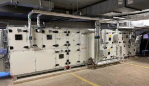 Large commercial HVAC air handling units and ductwork in a mechanical room, serviced by Furnace Doctors Heating & Air Conditioning LLC in Champaign, IL