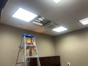 Chapman HVAC servicing a commercial HVAC unit visible through an open ceiling tile in Cleveland, OK.