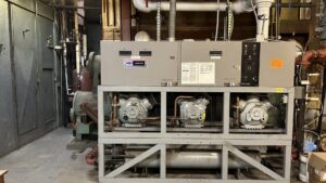 A large commercial HVAC chiller unit with multiple compressors in a mechanical room, serviced by Service Kings Heating and Air in Jamestown, ND.