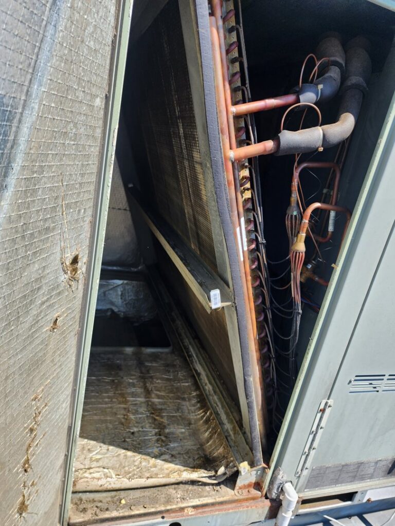Interior view of a commercial HVAC unit showing coils and insulation during inspection by Comfort Zone Mechanical in Antioch, TN.