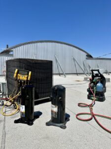 Commercial rooftop HVAC unit with new compressors and diagnostic tools, indicating a repair by Texas Air & Heat in Arlington, TX.
