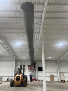 Workers installing large circular HVAC ductwork in a commercial building by Alpha HVAC LLC in Alexandria, LA.