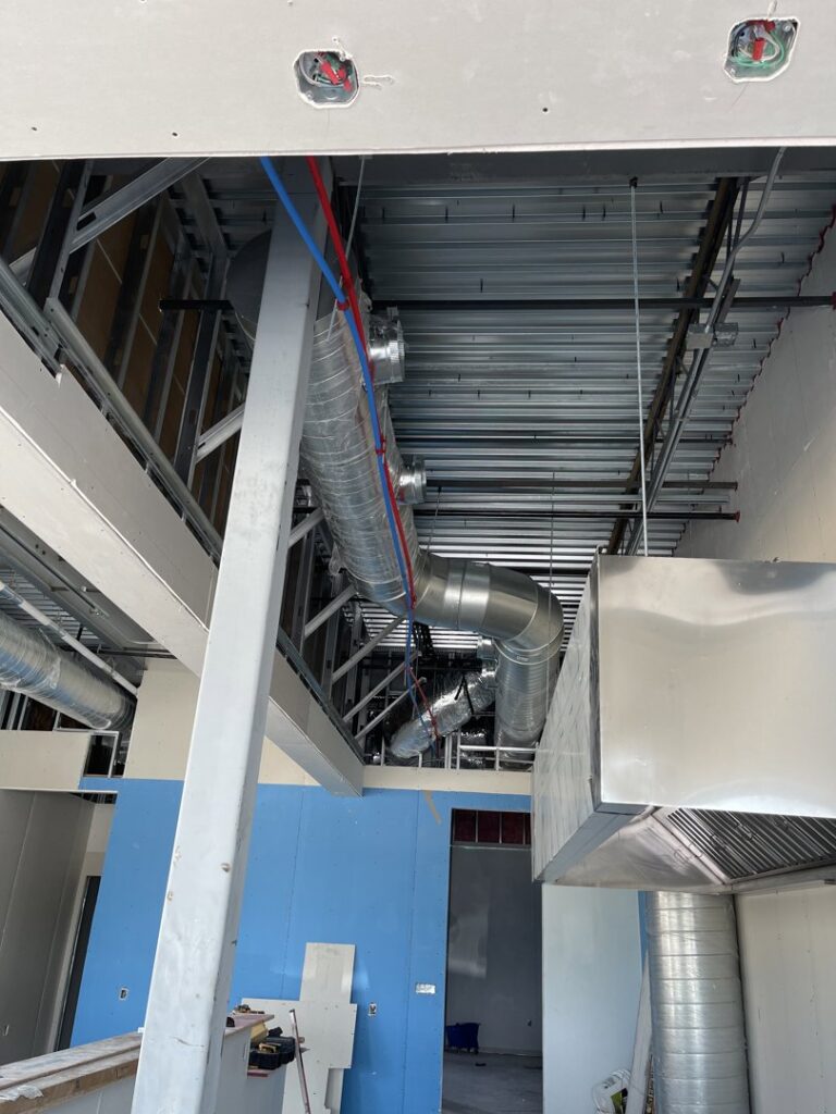 Exposed HVAC ductwork and piping being installed in a commercial building under construction by Jupitair in Frisco, TX.
