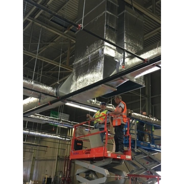 HVAC technicians installing large commercial ductwork from scissor lifts for Ware's Heating & Cooling in Georgetown, KY.