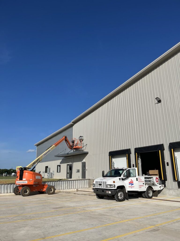 An Emergency Air service truck at a commercial HVAC installation site with a boom lift in Chandler, AZ.