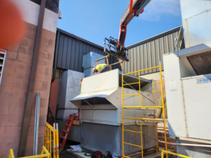A worker installing a large commercial HVAC unit with a lift and scaffolding for Capitol Heating and Air in Morgantown, PA.