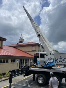 A crane lifting a new commercial HVAC unit onto a rooftop for installation by Blue Air Heating and Cooling in Orlando, FL.