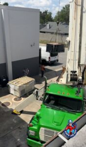 A crane lifting a large commercial HVAC unit during installation by QUICK AIR USA in Orlando, FL.