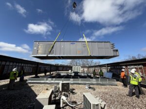 A large commercial HVAC unit being installed by crane onto a rooftop by Modern Mechanical HVAC in Garner, NC.