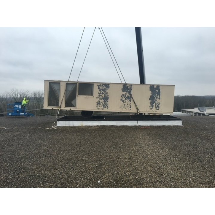 A large commercial HVAC unit being lifted by a crane onto a rooftop for installation by Ware's Heating & Cooling in Georgetown, KY.