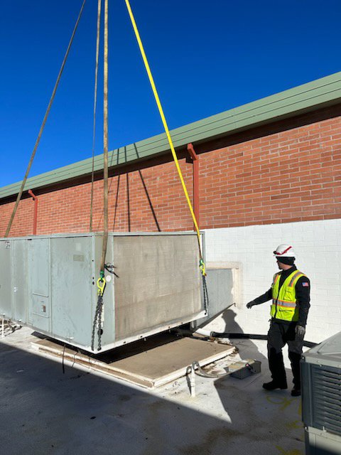 A large commercial HVAC unit being lifted by a crane onto a rooftop for installation by 365 Mechanical in Mesa, AZ.
